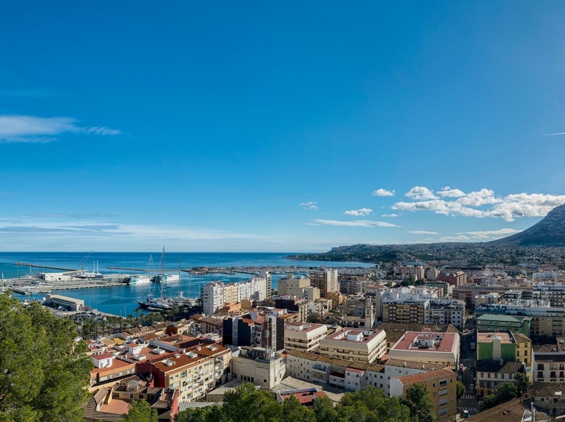 Vista aérea de hotéis na orla, com porto e mar azul.