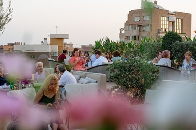 a group of people sitting on a patio with a building in the background - 