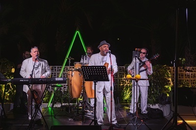 a group of men are playing instruments in front of a korg keyboard - 