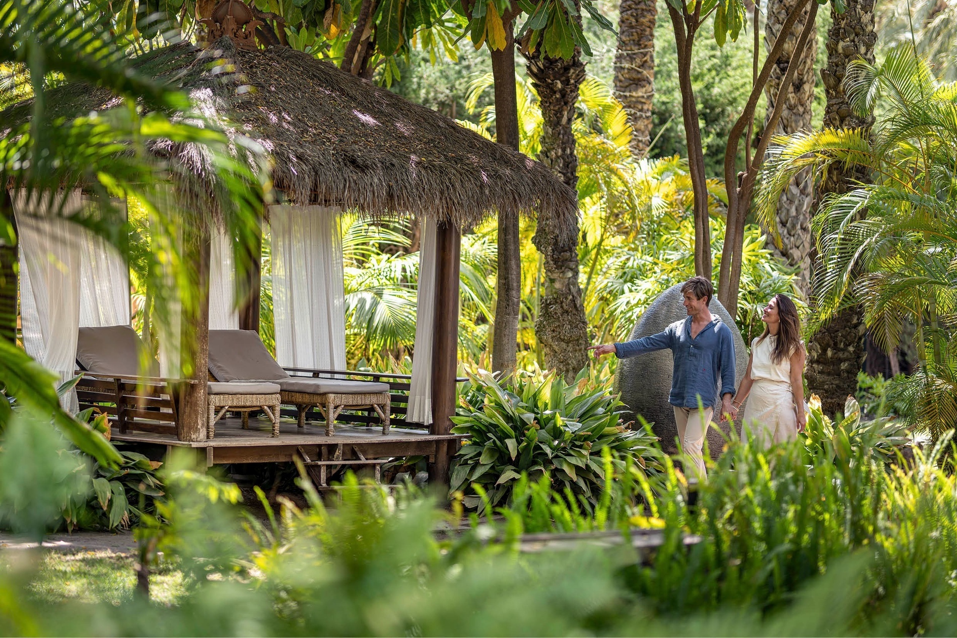a man and woman holding hands in front of a hut