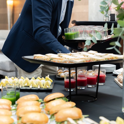 a man carrying a tray of sandwiches and drinks