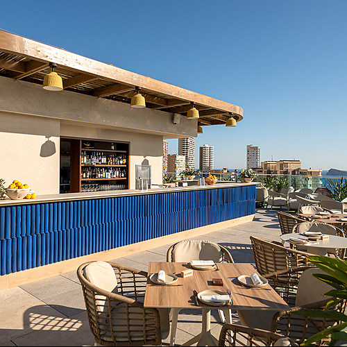 Bar y terraza de hotel Port Hotels: Corporativa con vistas al mar, mobiliario de mimbre y azulejos azules.
