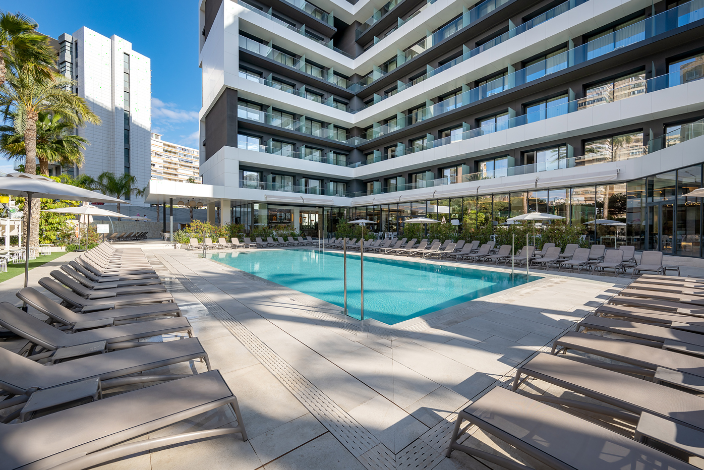 una piscina rodeada de sillas y sombrillas en un hotel