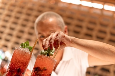 a bartender prepares a drink with straws and basil - 