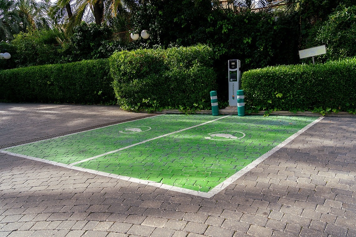 a green and white parking space with a charging station in the background