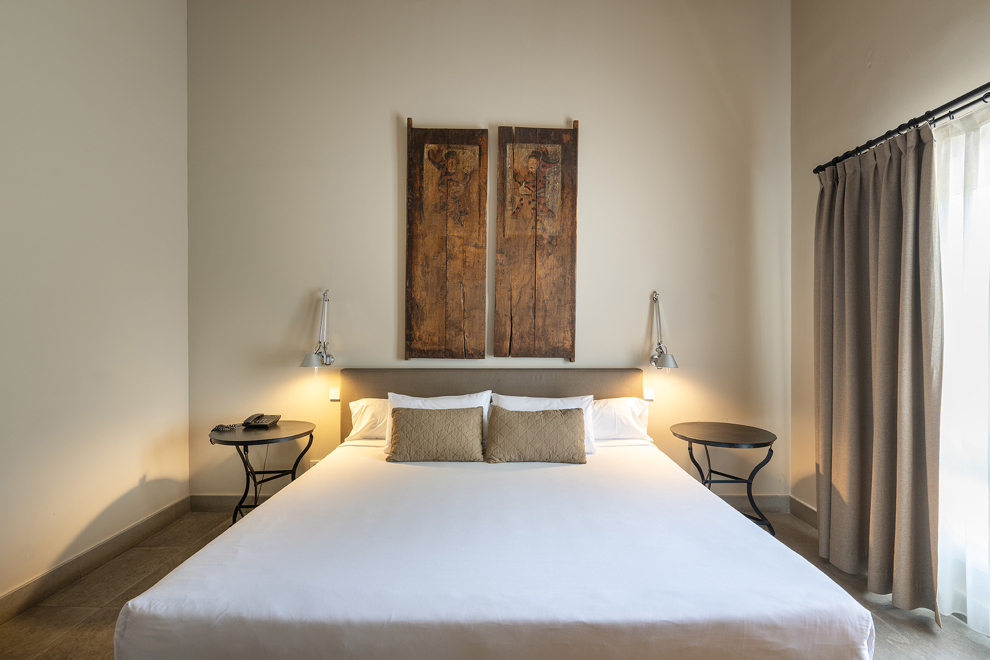 Habitación de hotel con cama grande, mesas de noche, lámparas y cortinas. Port Hotels: Huerto del Cura