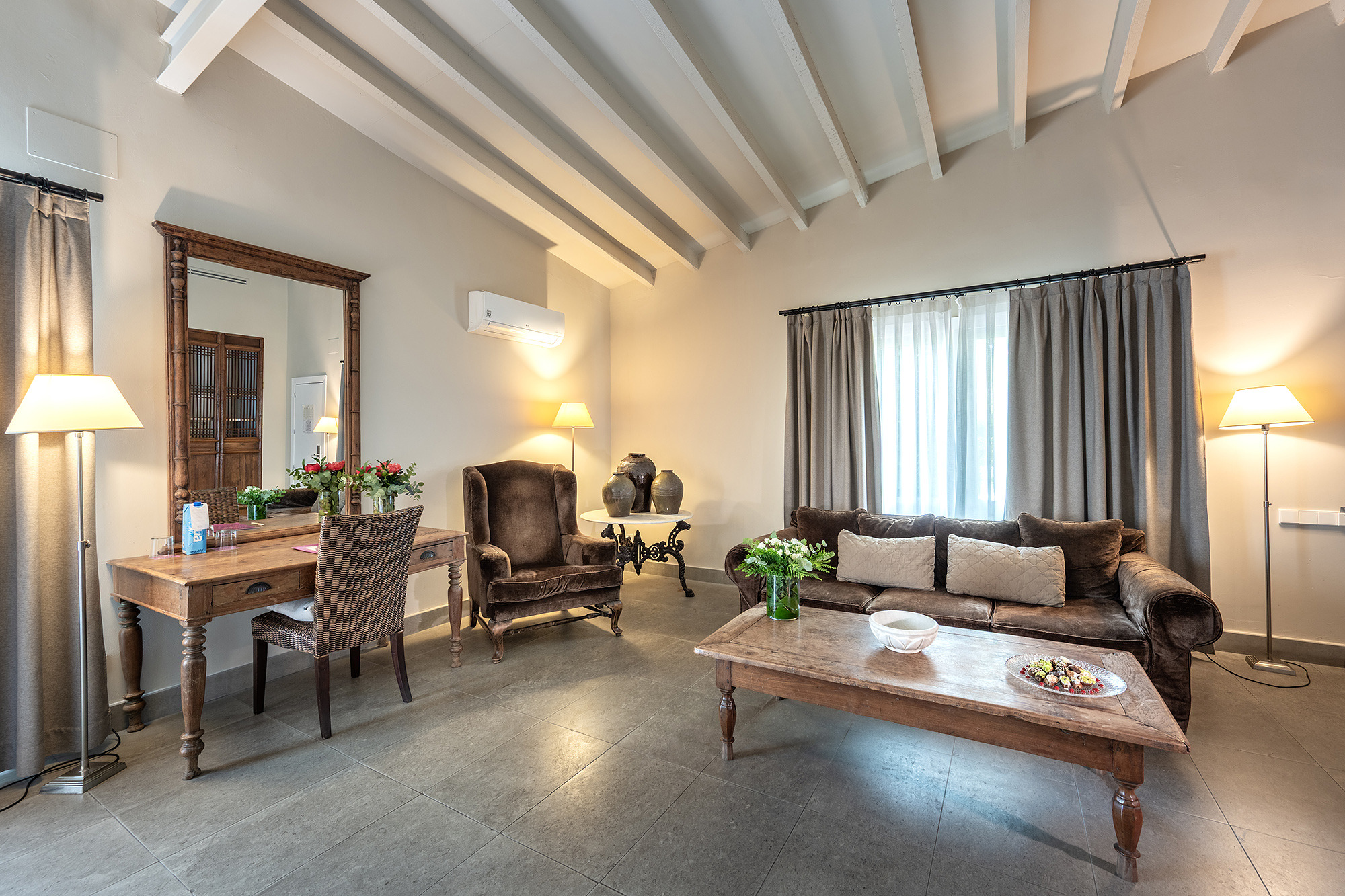 Elegante sala de estar del hotel con sofá marrón, sillón, mesa de centro y escritorio de madera. Port Hotels: Huerto del Cura.