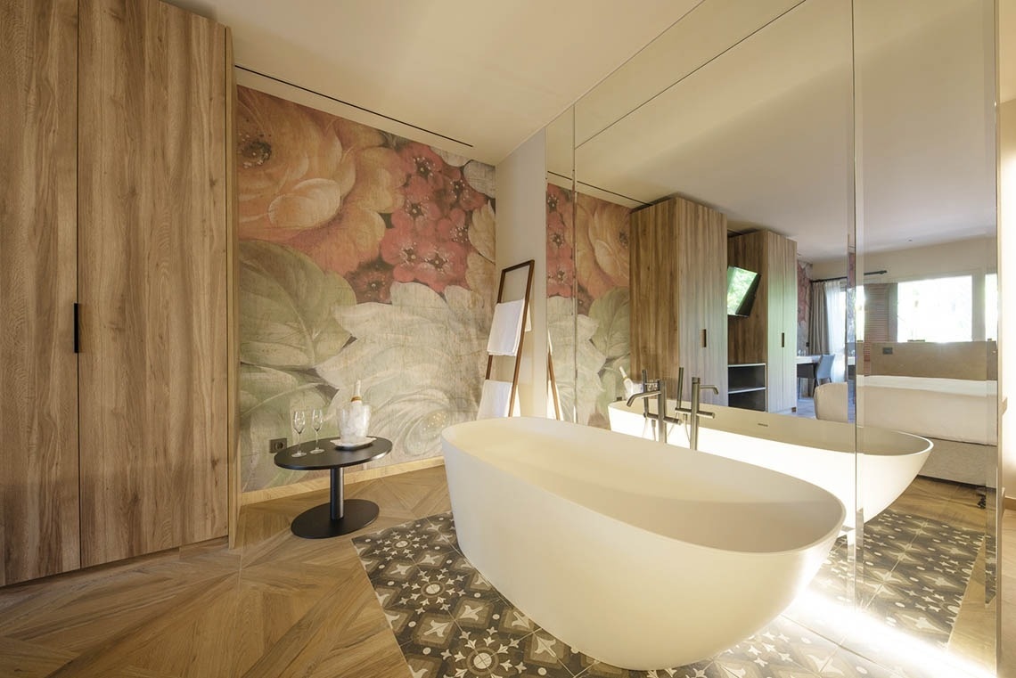 a bathtub in a bathroom with a floral wallpaper on the wall