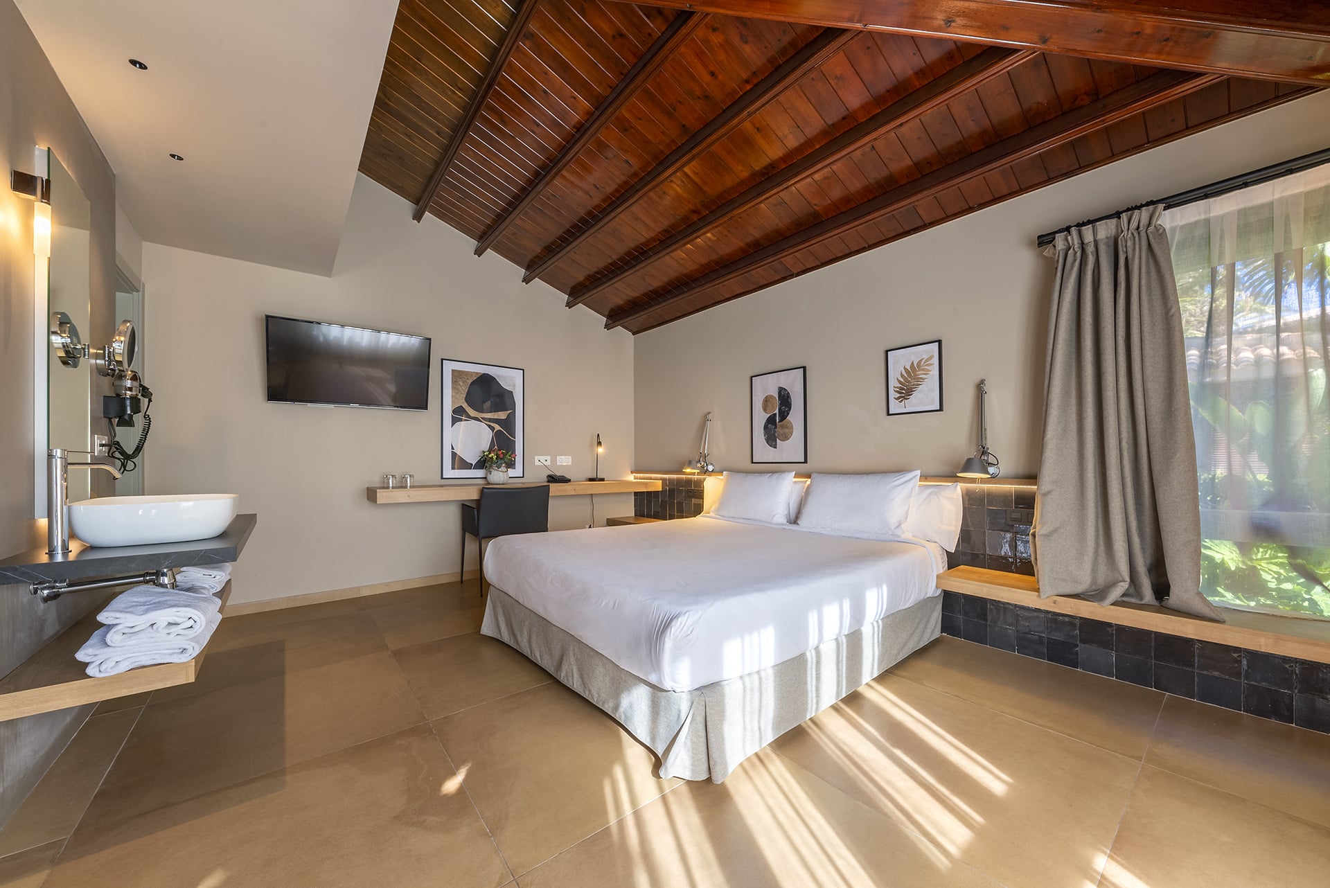 Chambre d'hôtel moderne avec lit king-size, salle de bain et plafond en bois. Idéal pour votre Port Hotels: Huerto del Cura.