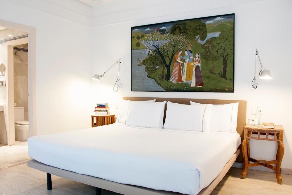 a bedroom with a large painting on the wall above the bed