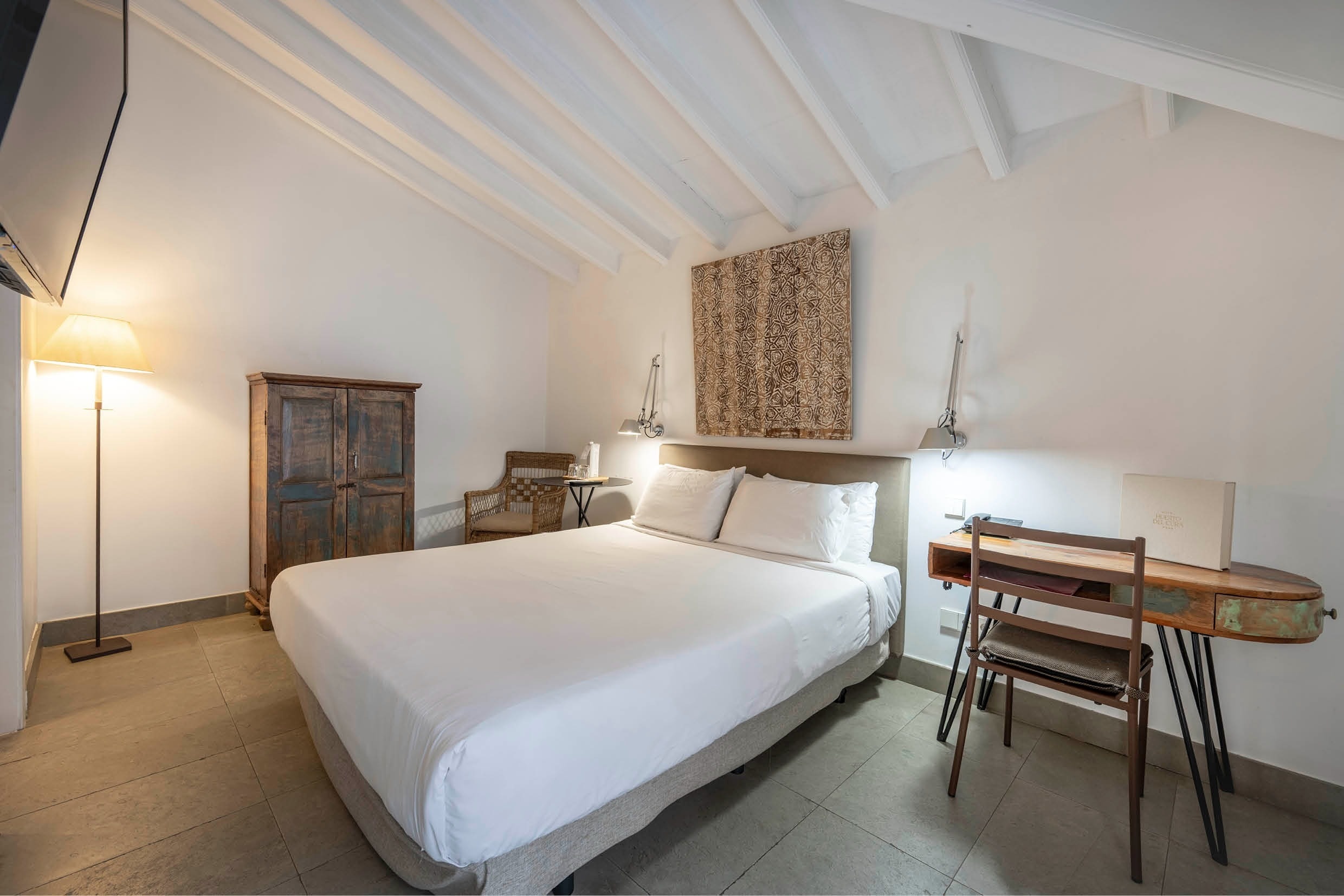 una habitación con una cama blanca y un escritorio de madera