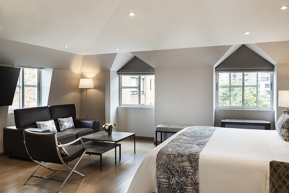 Suite moderna con sala y cama King. Porton de la Cabrera, ventanas, sofá, mesa de centro.