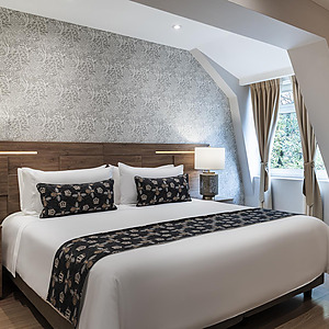 Cama King en habitación con papel tapiz floral yPorton de la Cabrera.
