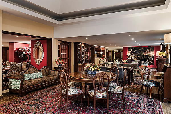 Sala de espera de hotel con sillones Porton de la Cabrera, sofás de cuero, alfombra persa y mesa de centro.
