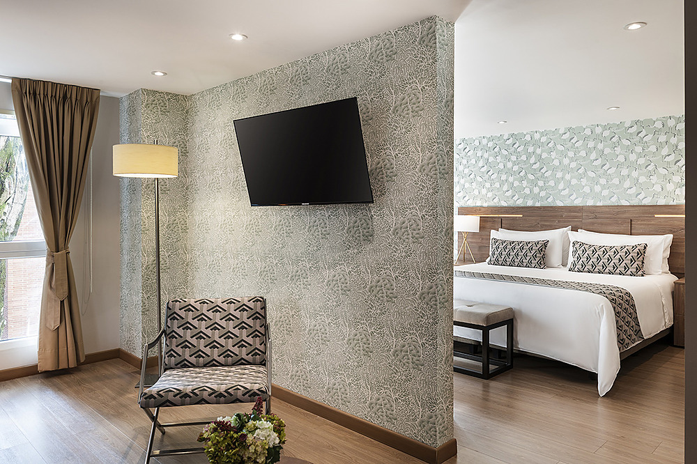 Amplia habitación de hotel con Porton de la Cabrera, TV, silla decorativa y cama espaciosa.
