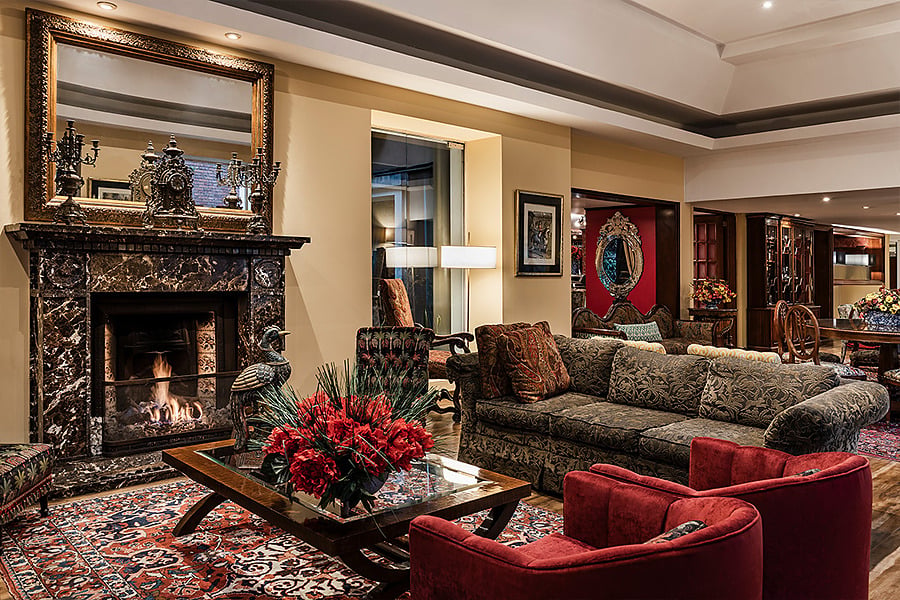 Sofá de lujo con cojín turquesa y espejo ornamentado en hotel, ideal para relajarse en Porton de la Cabrera.