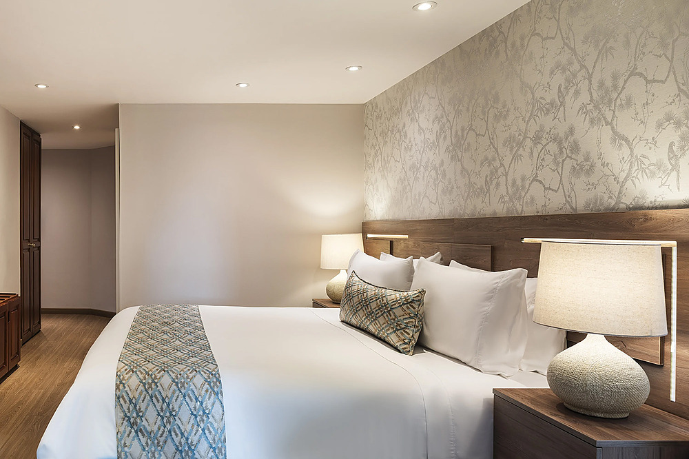 Habitación de hotel con cama grande, papel tapiz floral yPorton de la Cabrera.