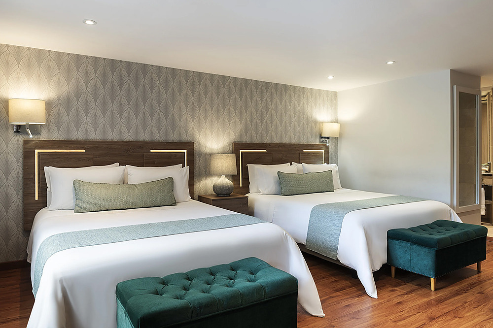 Habitación de hotel con dos camas, mesitas de noche y Porton de la Cabrera.