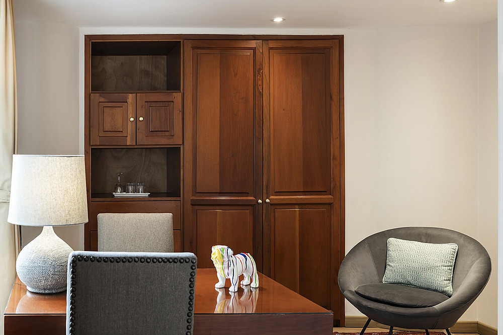Escritorio con lámpara, silla y arte decorativo en habitación de hotel. Porton de la Cabrera.