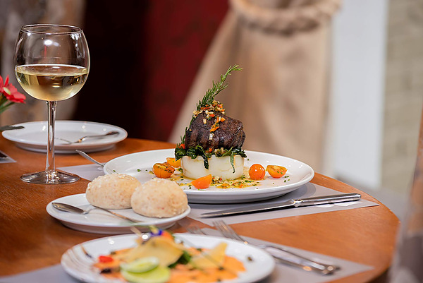 Vista de cerca de un plato de carne con puré, tomates y pan, perfecto para Porton de la Cabrera.