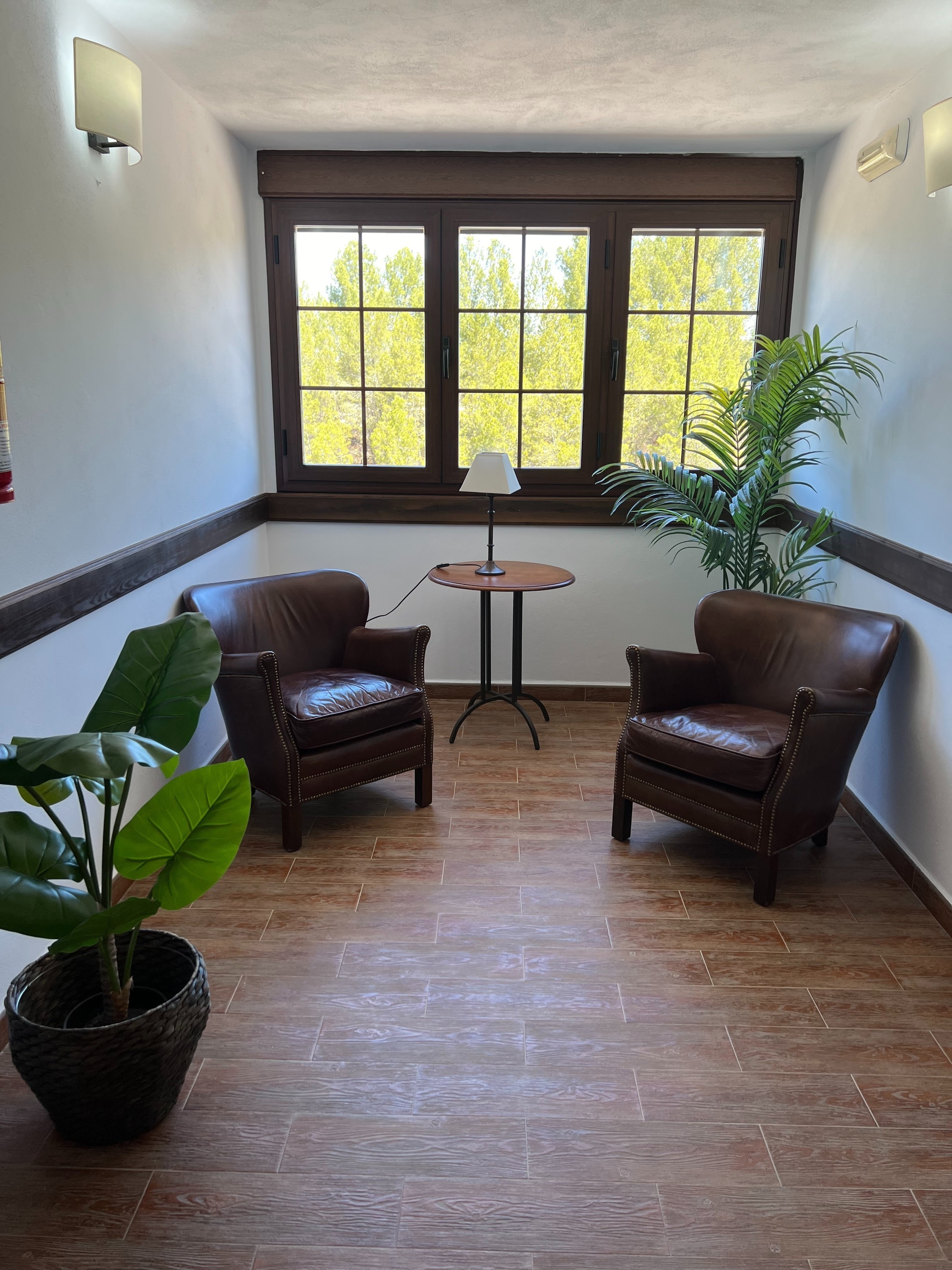 a room with two chairs and a table with a lamp on it