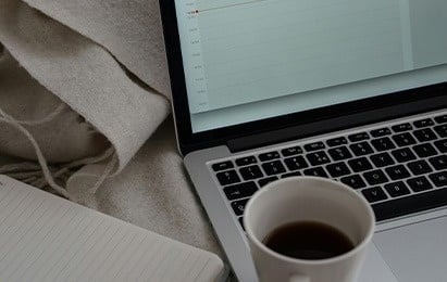 una taza de café está sentada frente a una computadora portátil .