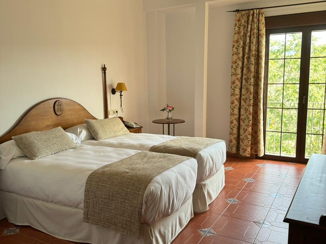 una habitación con dos camas y una ventana con cortinas florales