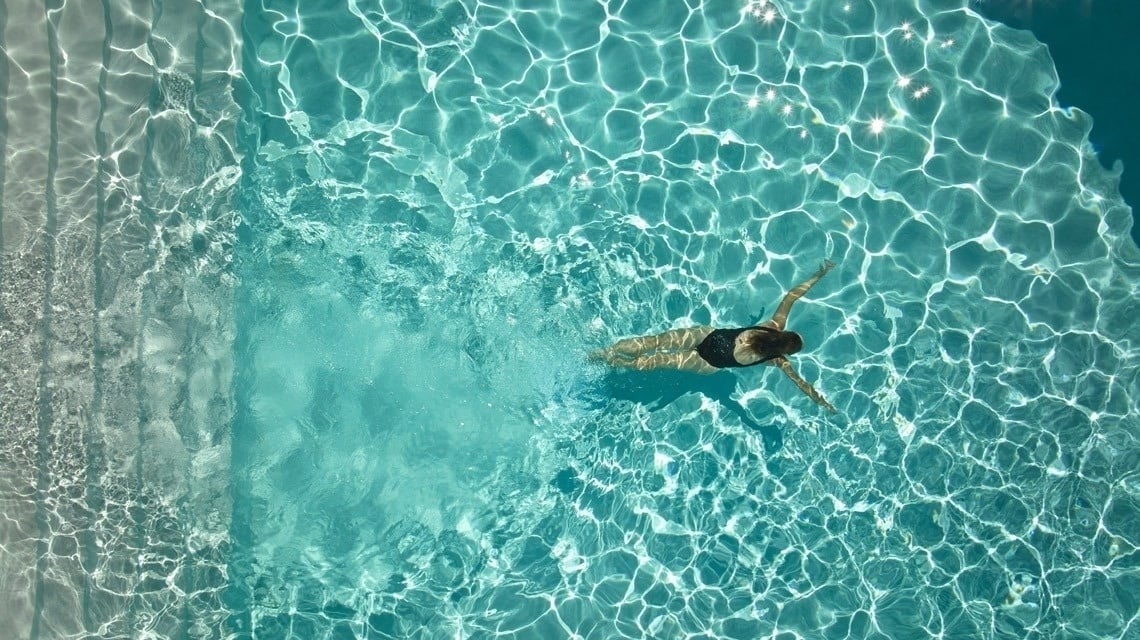 a woman in a black bathing suit is swimming in a pool