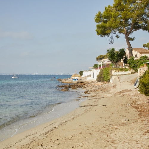 una playa con un pequeño bote en el agua