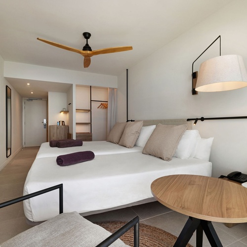 una habitación de hotel con dos camas y una mesa de madera