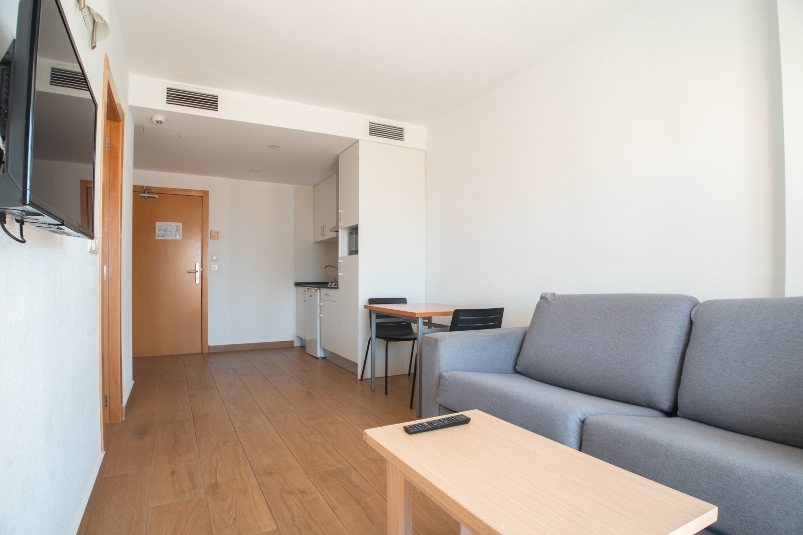 Apartamento moderno en Primavera Loix Apartamentos con sofá gris, mesa y cocina.