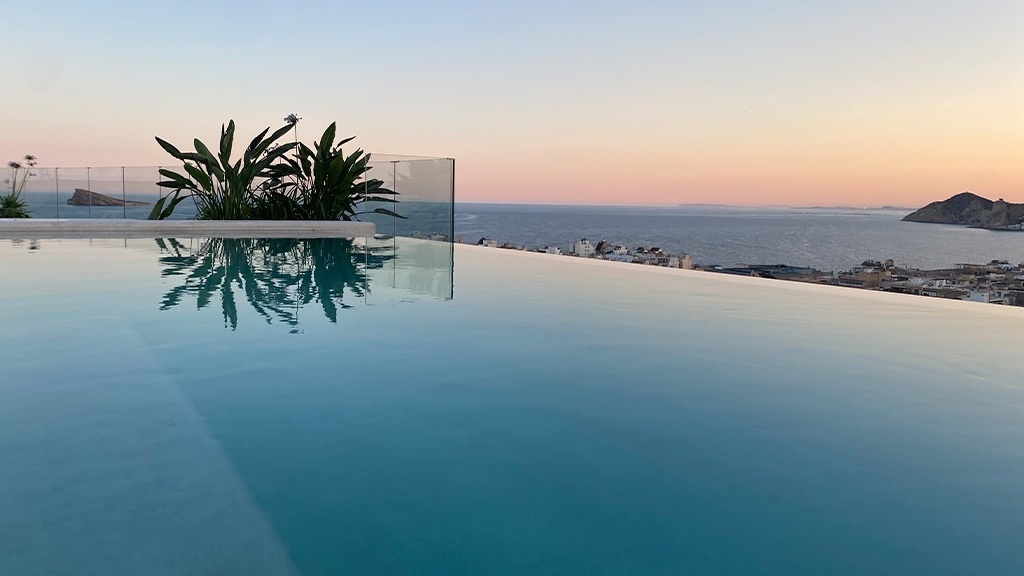 a swimming pool with a view of the ocean at sunset