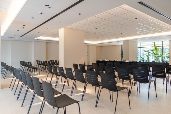 rows of black chairs are lined up in a conference room