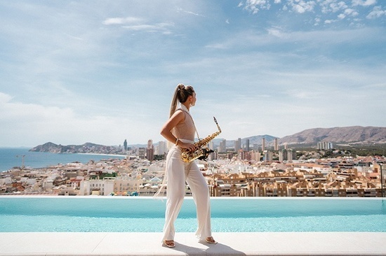 a woman playing a saxophone in front of a city