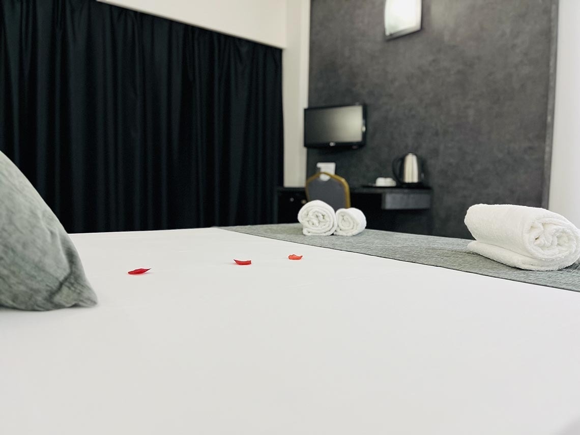 una cama con toallas y pétalos de rosa en la cama