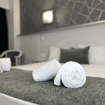 a bed with a gray blanket and white towels on it