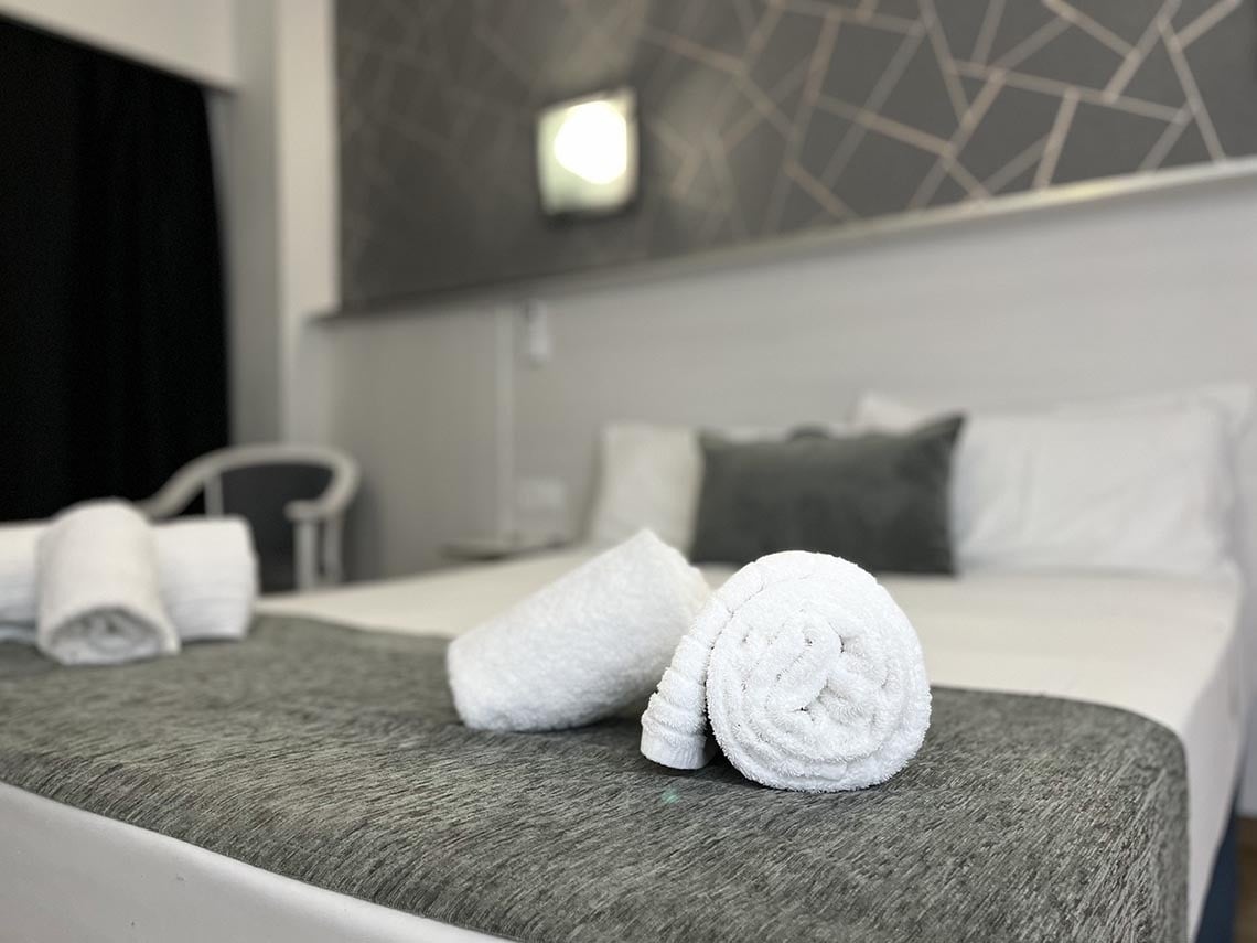 a bed with a gray blanket and white towels on it