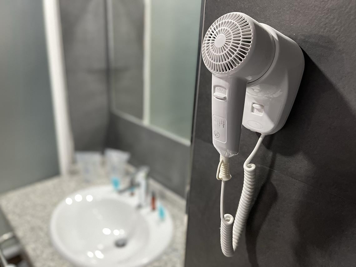 un secador de cabello está colgando de una pared en un baño