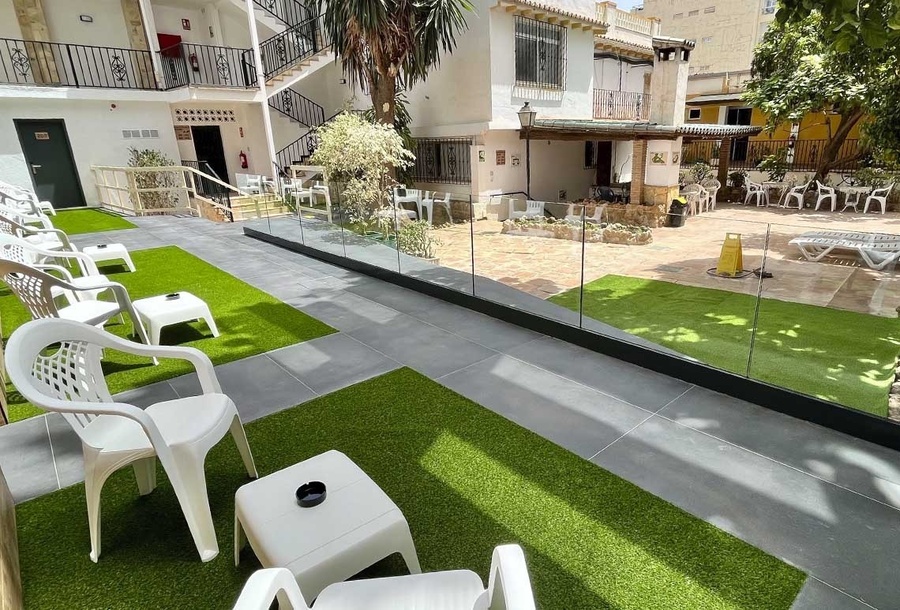 a patio with white chairs and tables in front of a building