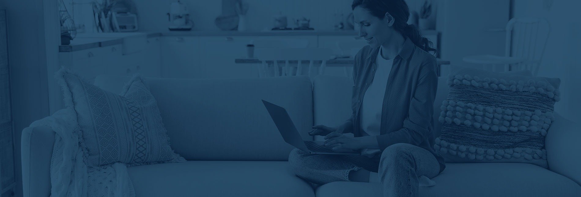 a woman is sitting on a couch using a laptop