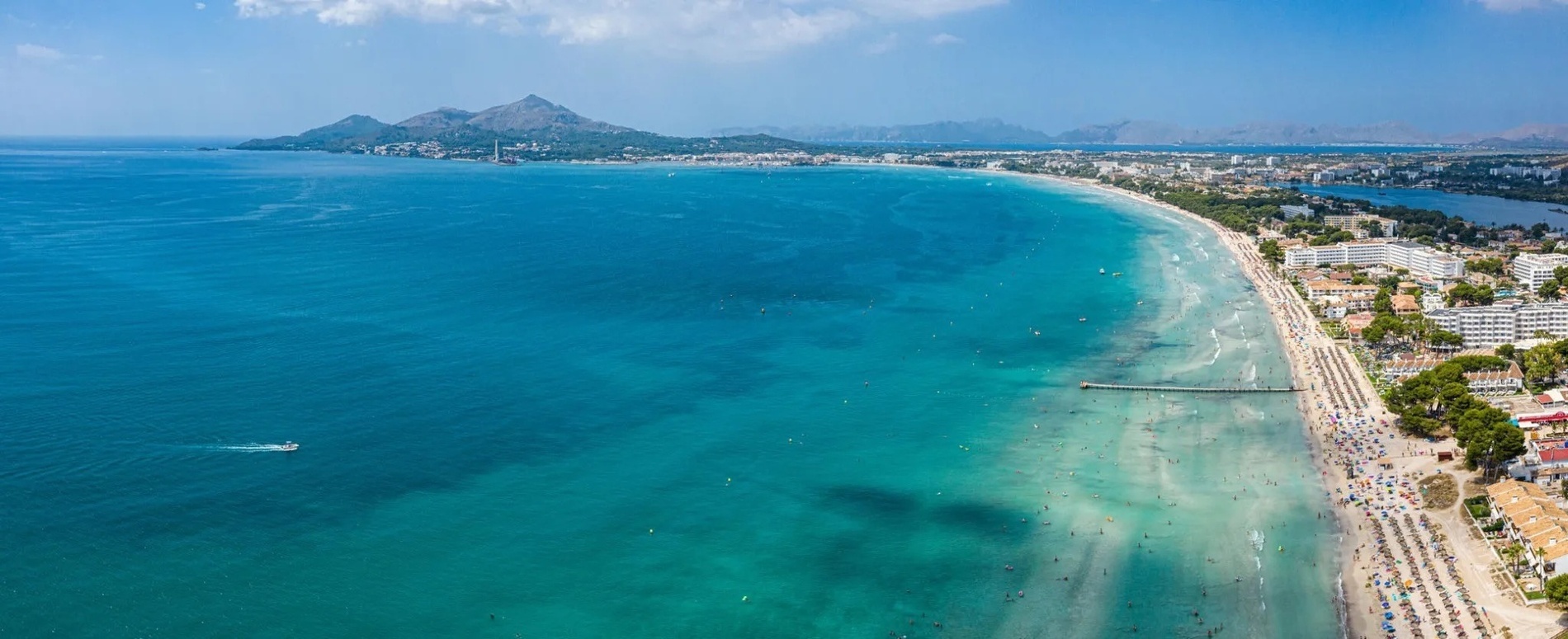 an aerial view of a beach with mountains in the background