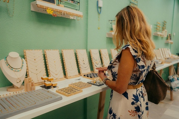 una mujer está mirando collares y anillos en una tienda