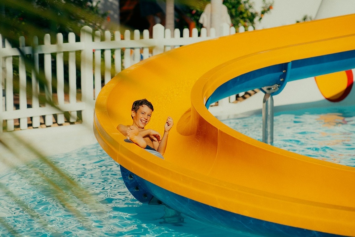 a boy is smiling while going down a water slide