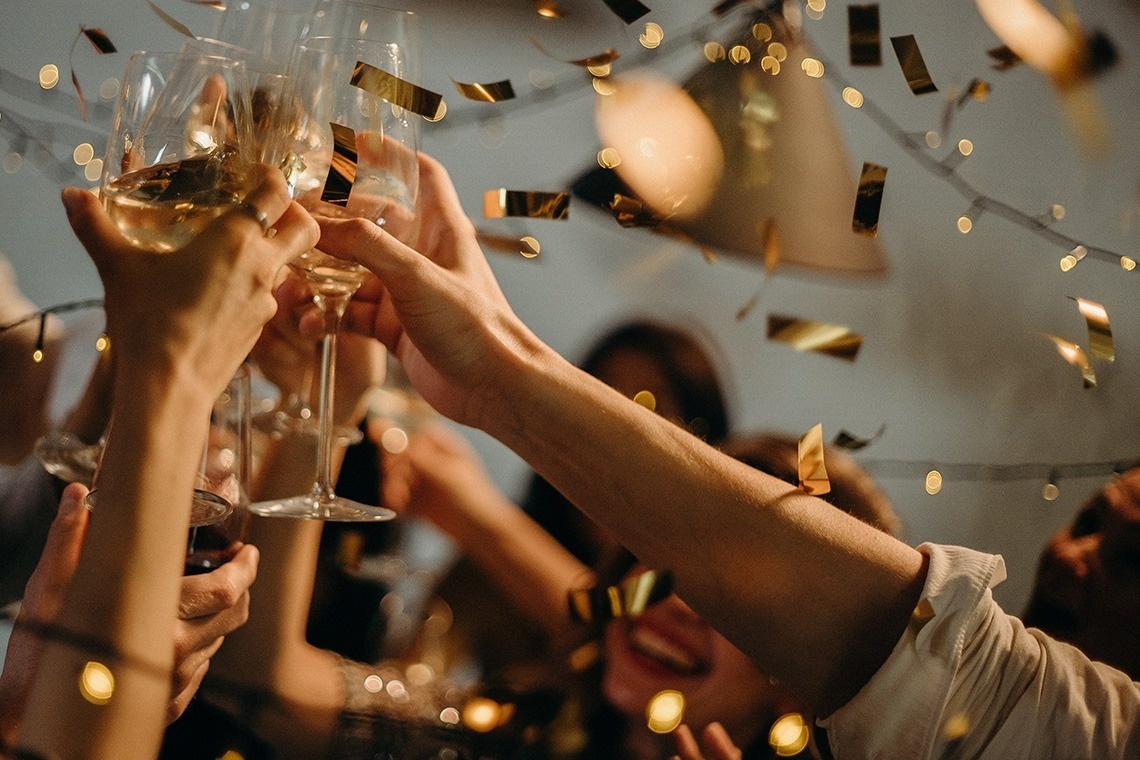 a group of people toasting with wine glasses and gold confetti