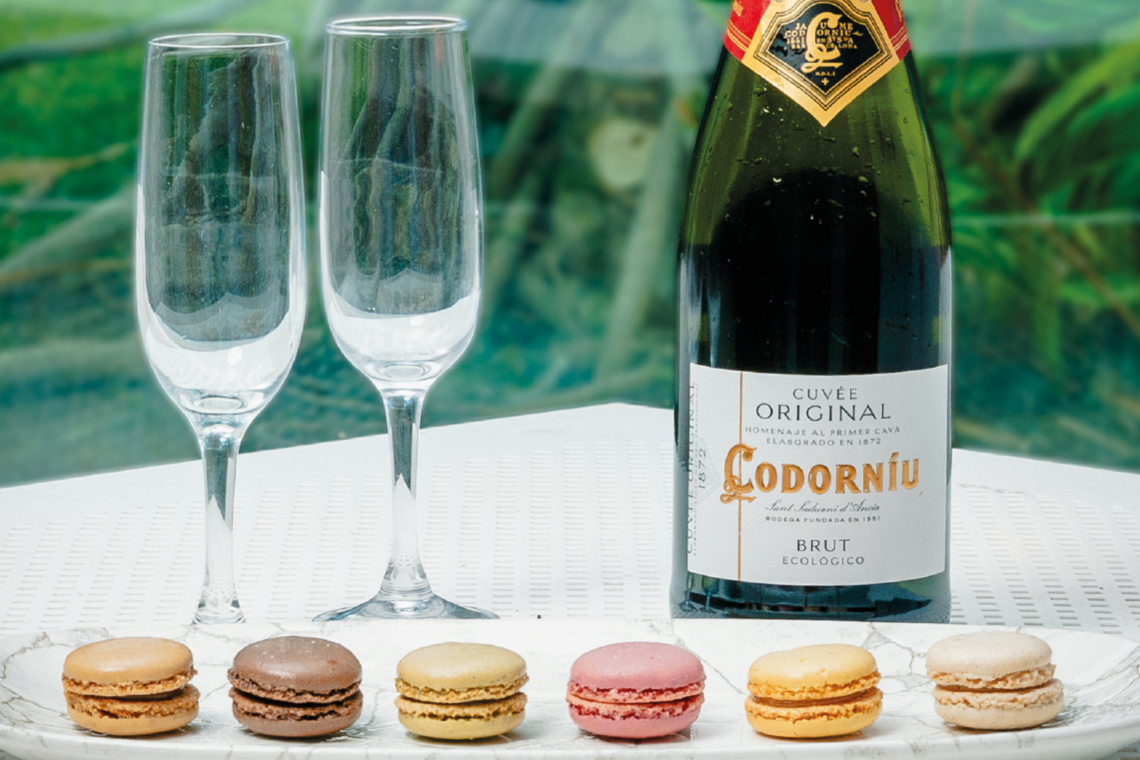 a bottle of codorniu brut sits next to a plate of macarons