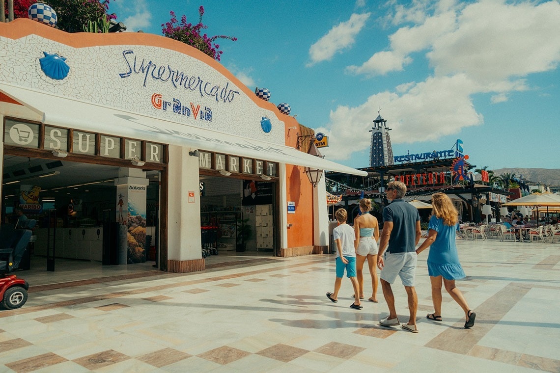 a group of people walking in front of a supermarket