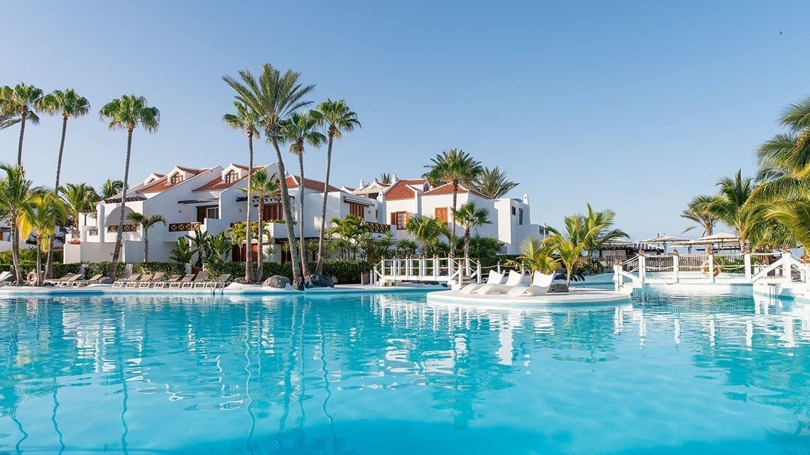 una gran piscina rodeada de palmeras y edificios blancos