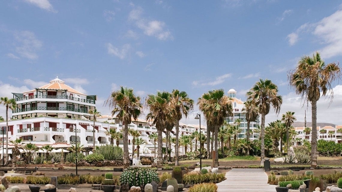un gran edificio blanco rodeado de palmeras y cactus