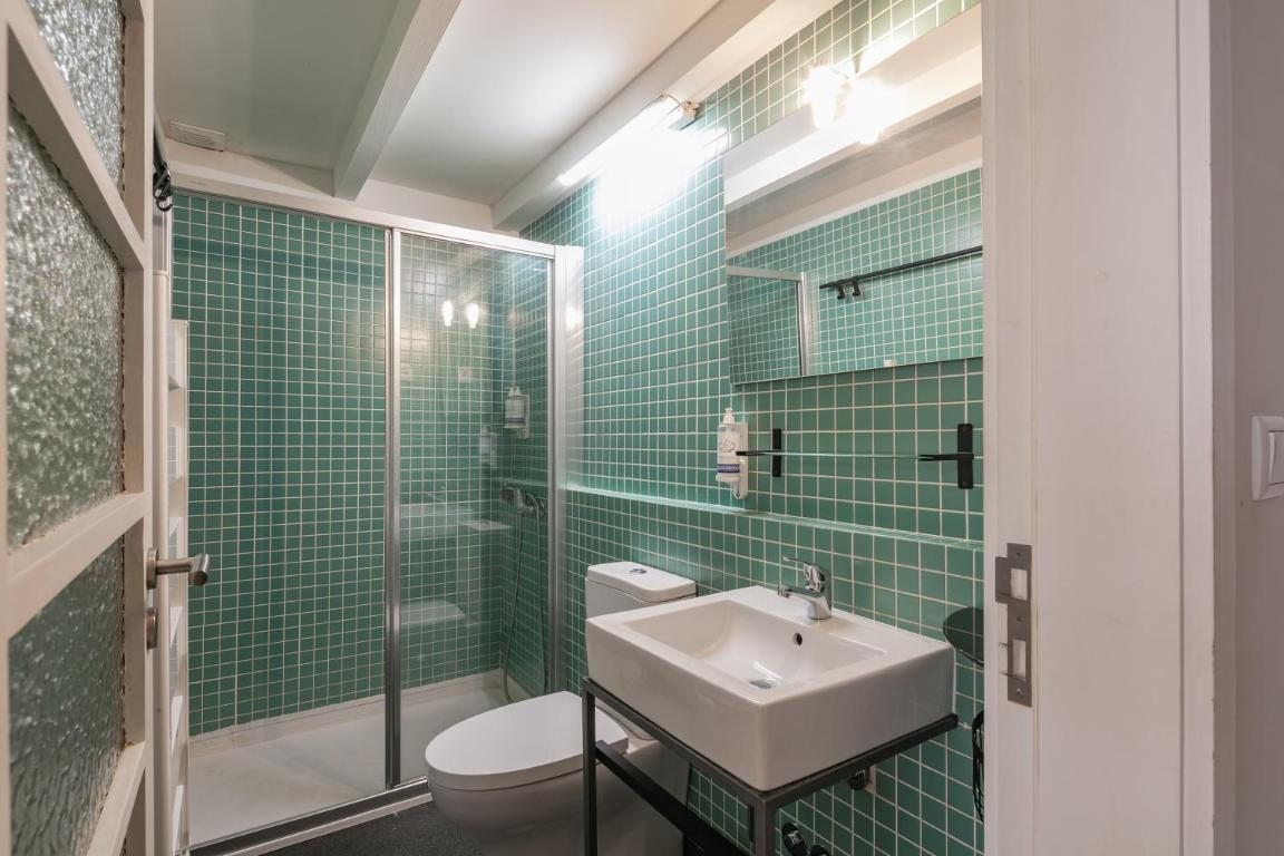 um banheiro com azulejos verdes e uma pia branca