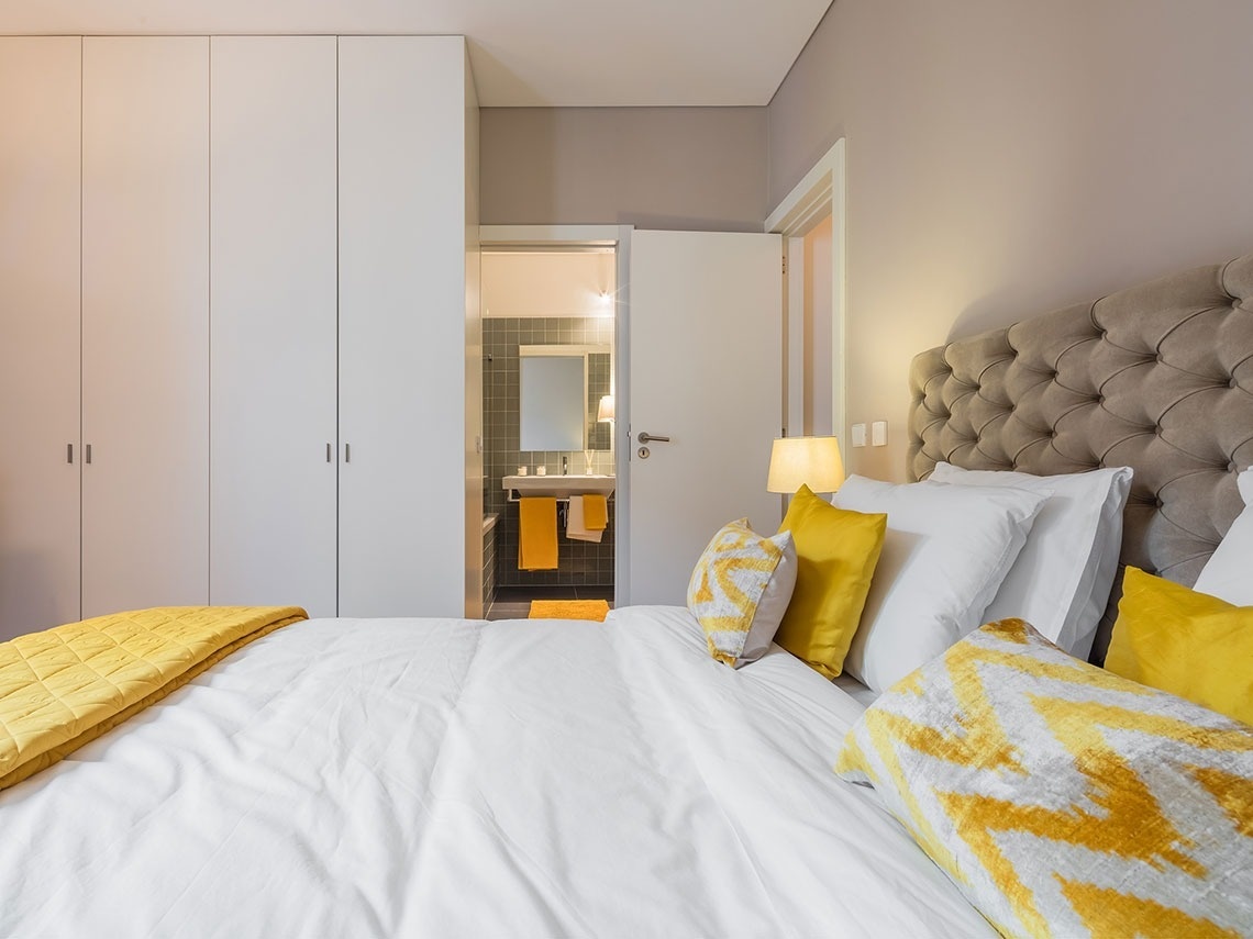 um quarto com cama branca e almofadas amarelas